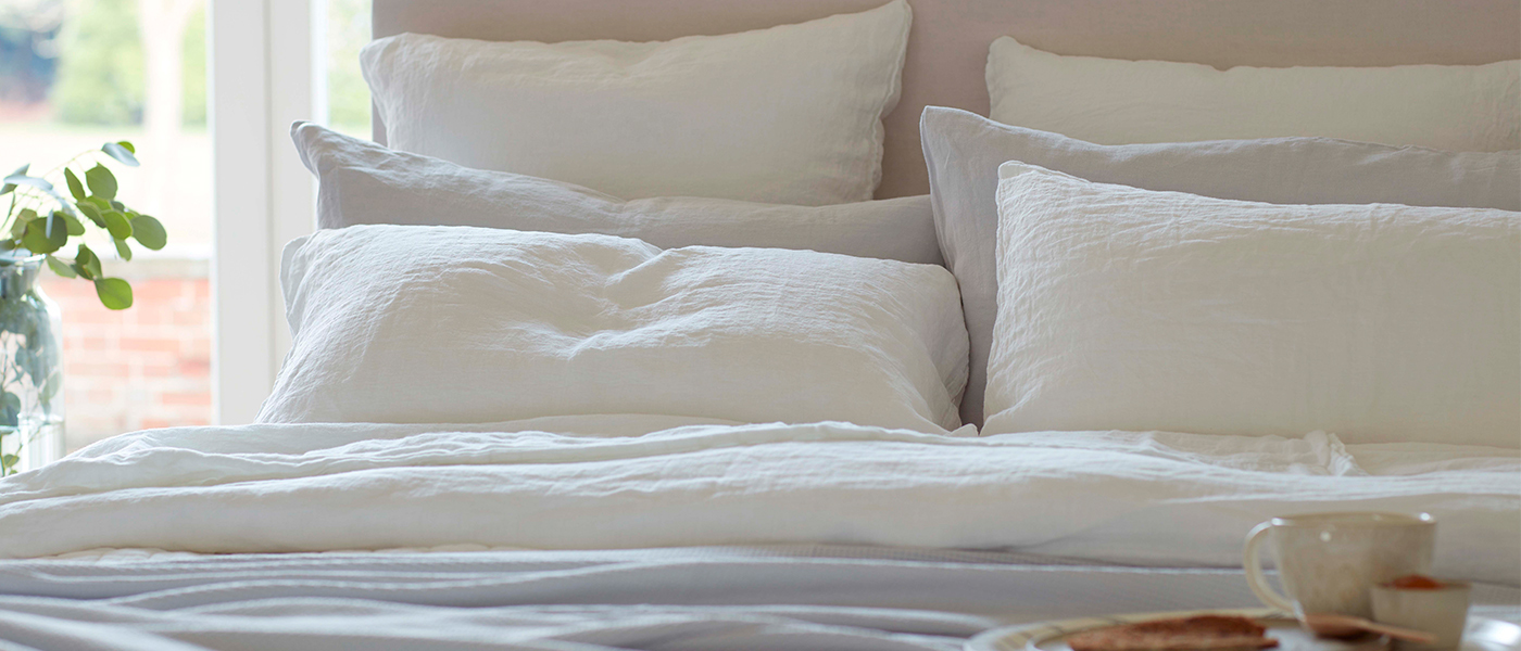 A summer bedroom with white linen bedding A summer bedroom with white linen bedding
